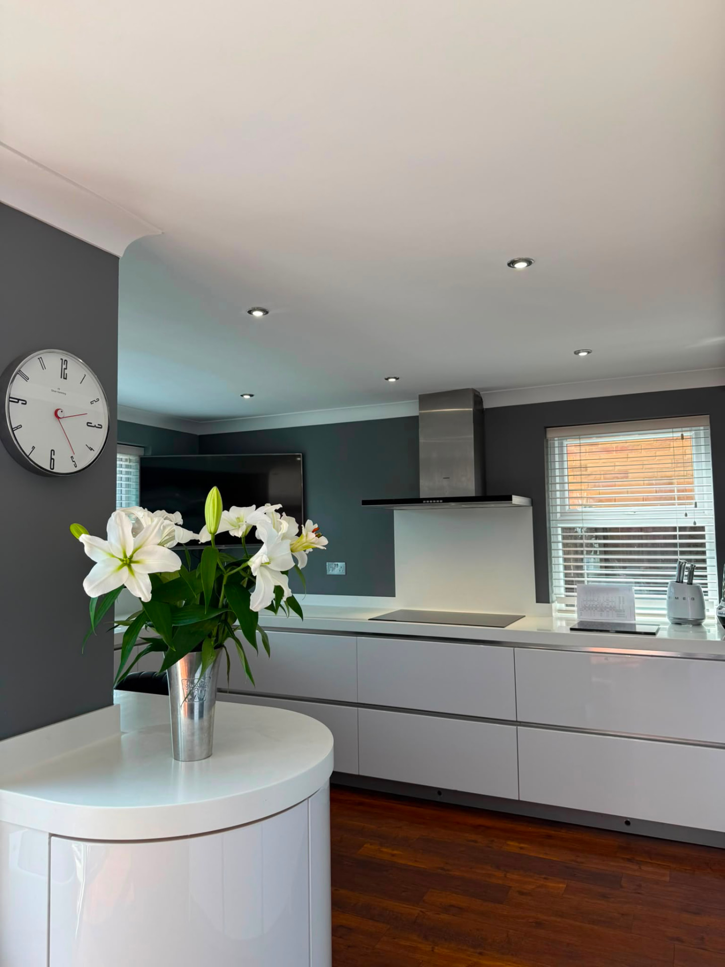 Open-plan kitchen with two-tone grey walls and a large wall clock, Brighton