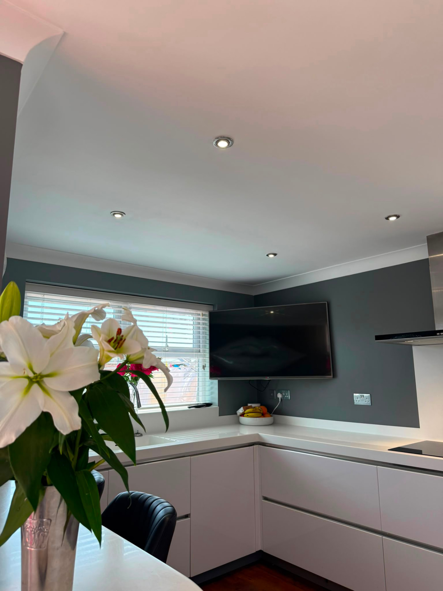 Open-plan kitchen with deep slate feature walls, white cabinetry and lilies, Brighton
